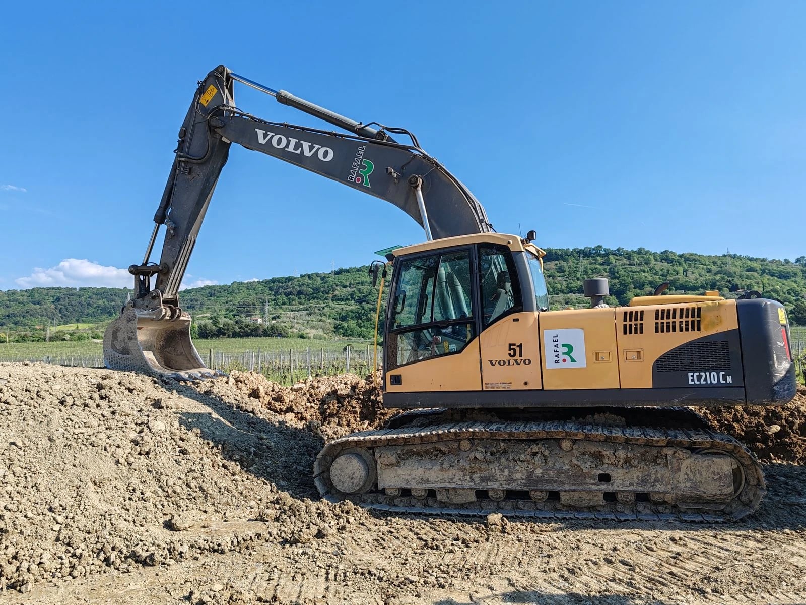 A hydraulic excavator uses its boom and bucket to dig material and load haul trucks.