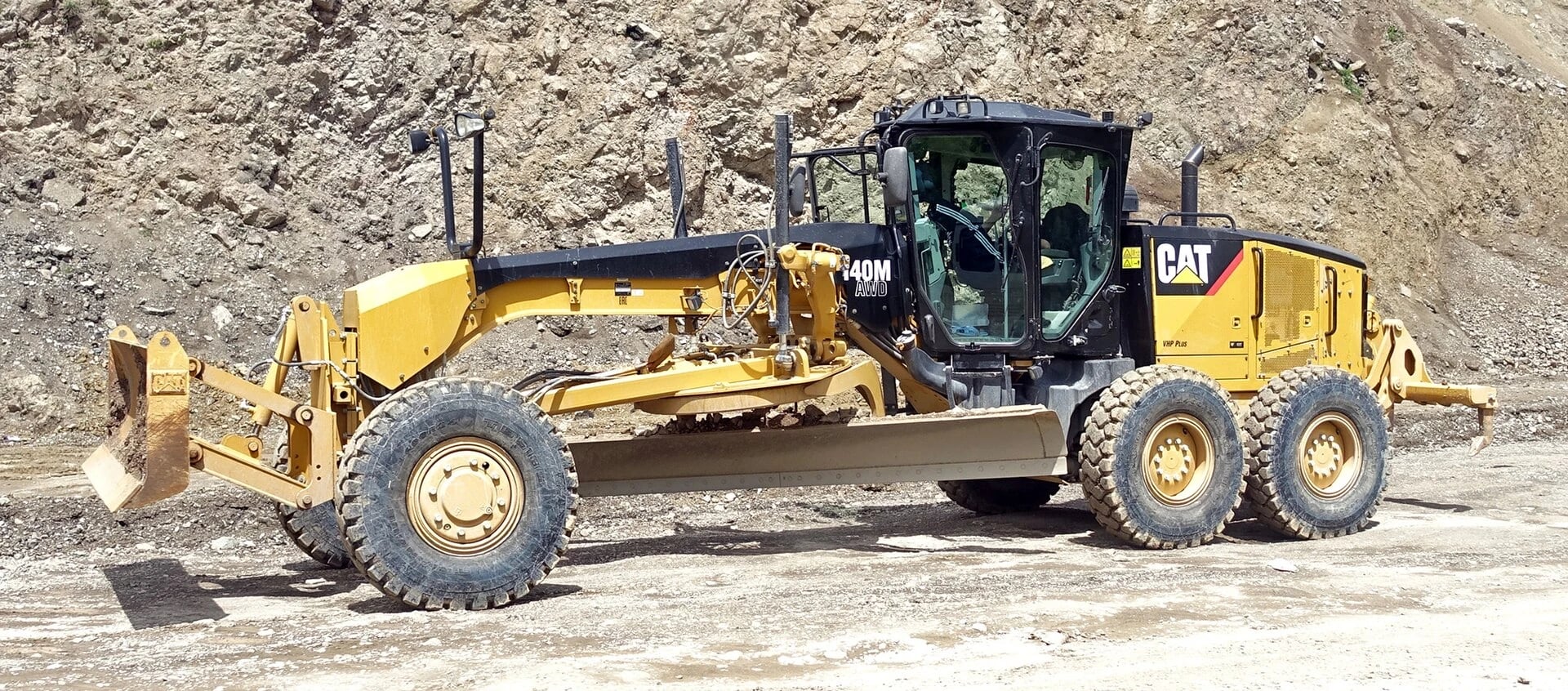 A motor grader shapes road surfaces and drainage slopes with an adjustable blade.