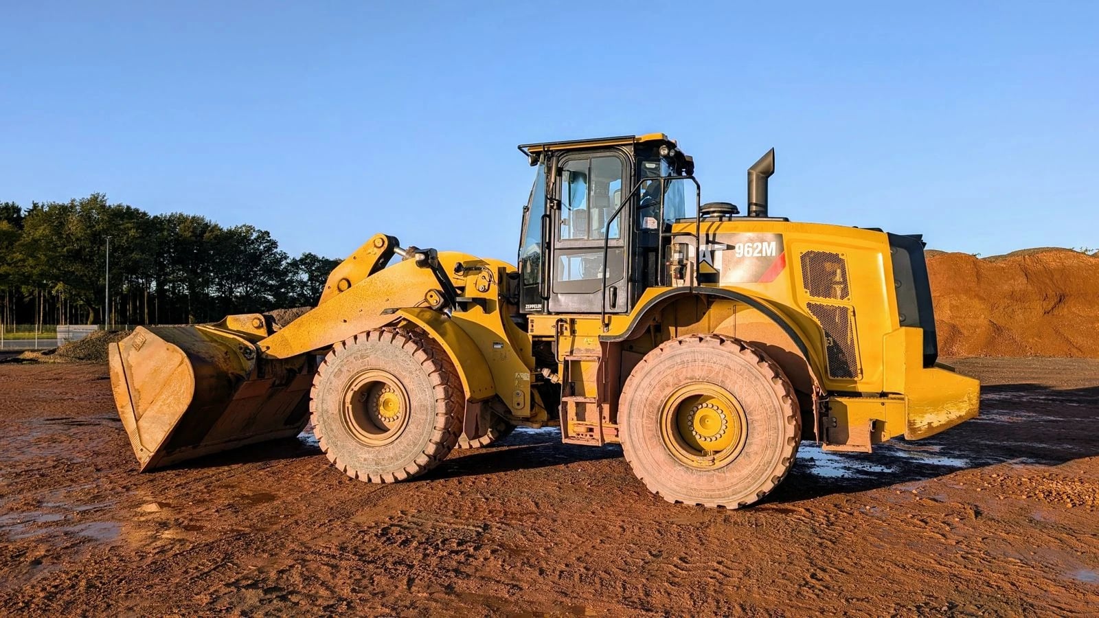 A wheel loader scoops loose material from stockpiles and loads it into trucks or feed hoppers.